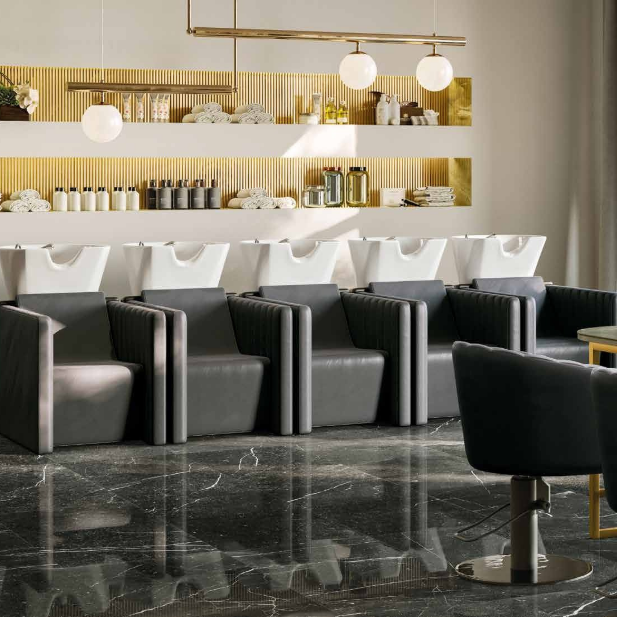 elegantan frizerski salon s nizom tamnosivih glavopera i bijelim umivaonicima, u prostoru sa zlatnim detaljima, visećom rasvjetom i mramornim podom