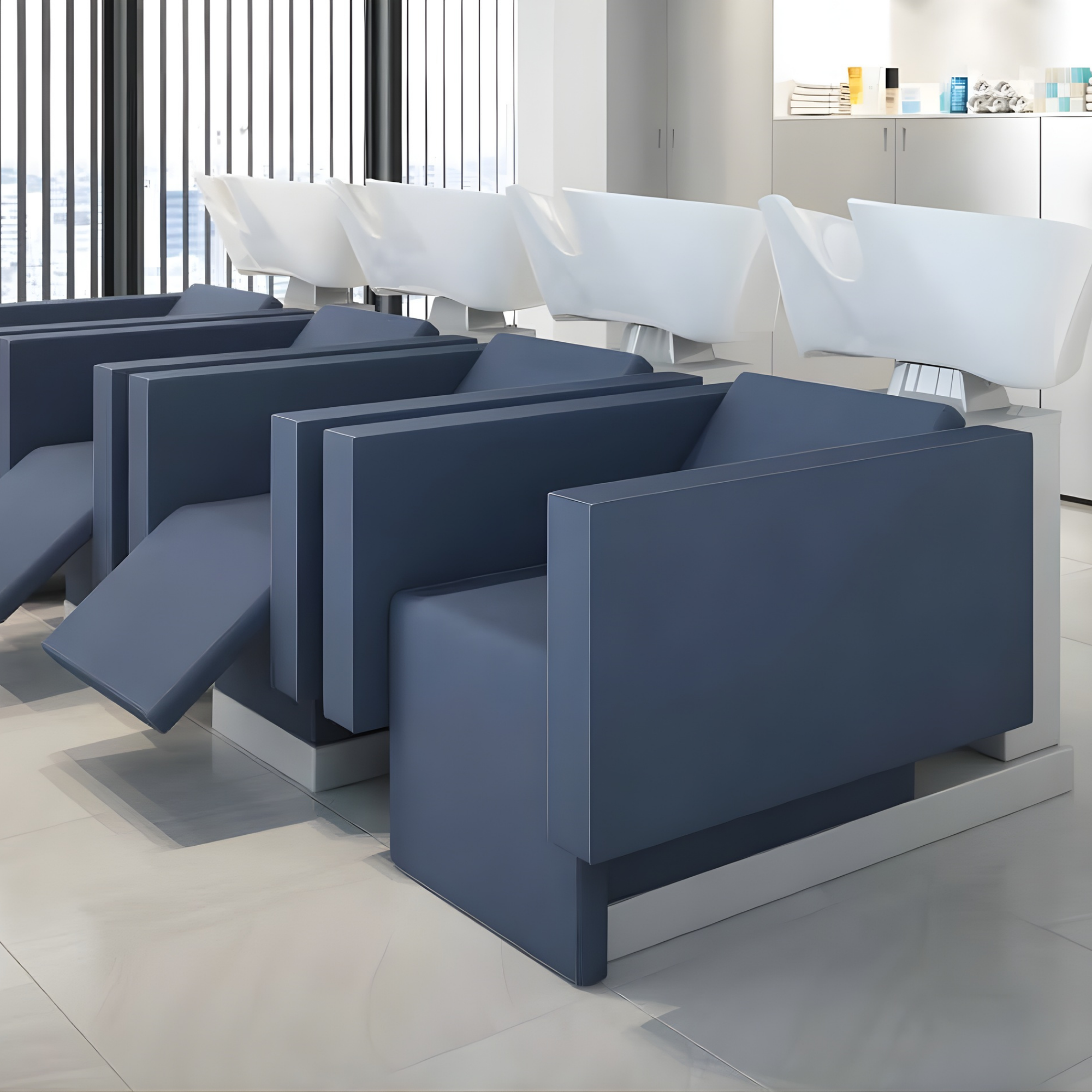 moderni frizerski salon s tri plava glavopera s naslonima za noge i bijelim umivaonicima u svijetlom minimalističkom prostoru